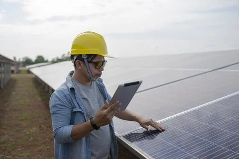 Technician uses a tablet to check the precision of solar energy to generate r Foto stock