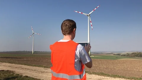 Technician uses tablet looking at wind turbine towers Stock Footage 96516049