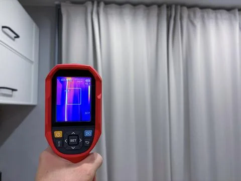 Technician uses thermal imaging camera to identify heat loss from window, e.. Stock Photos