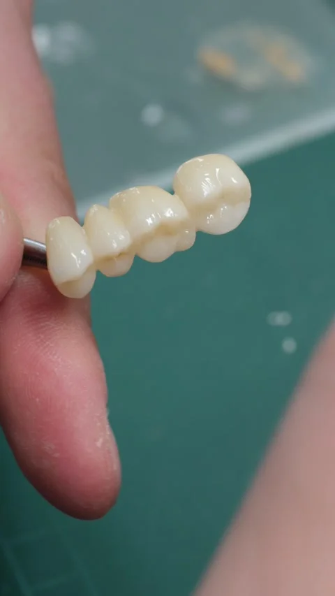 Technician uses thin brush to color teeth implant enamel adding shades in lab Stock Footage 320960182