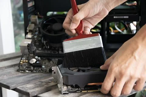 A technician is using a brush to clean the graphics card. Stock Photos