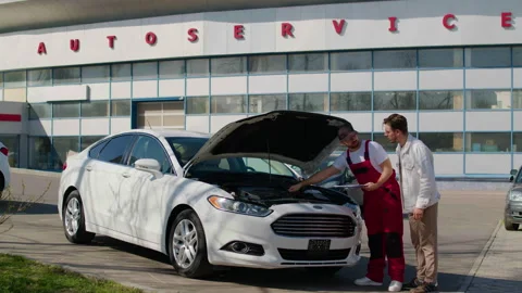Technician using diagnostic computer to identify engine problems on a white car Stock Footage 312515462