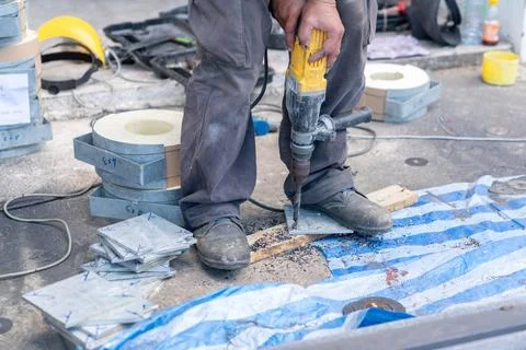 The technician is using a drill to bore holes in the steel plate that will .. Stock Photos