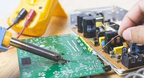 Technician is using electric soldering iron and the tin for repairing elect.. 写真素材