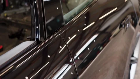 Technician using handheld 3D scanner on reflective car surface for automotive Stock Footage 336450344