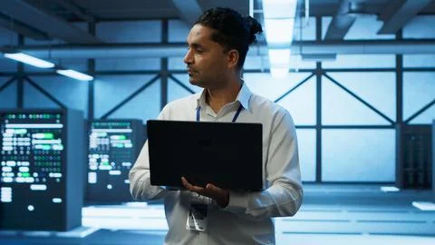 Technician using laptop in data center, managing servers Stock Photos