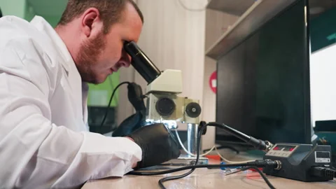 Technician Using Microscope to Inspect Circuit Board on Workbench Stock Footage 283122989