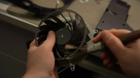 Technician using small brush to clean dust from game console cooling fan Stock Footage 310625742