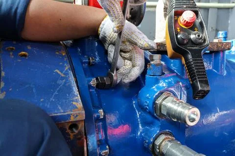 Technician Using a Wrench on Blue Machinery Fasteners. 库存照片