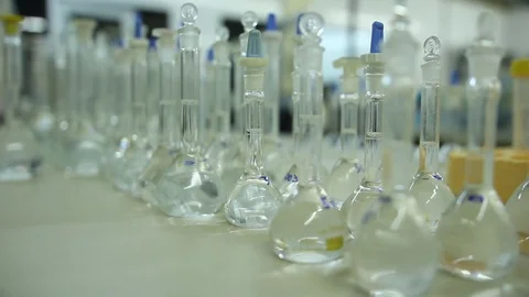 A technician verifies volumetric flasks in a labortory previous to chemical anal Vídeos de archivo 79049721