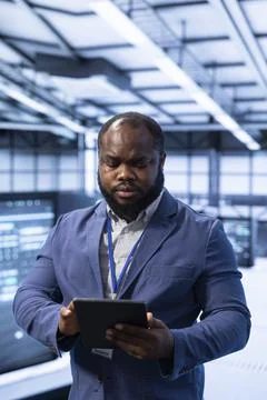 Technician walking in data center, using tablet to configure infrastructure Stock Photos