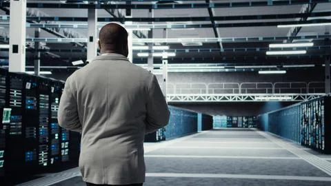 Technician walking in data center workplace with rows of mainframes 스톡 사진