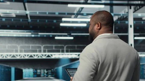 Technician walking in data center workplace with rows of mainframes Stockfoto's