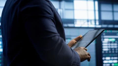 Technician walking in server room, doing checkup, inputting data on tablet Stock Photos