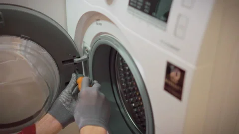 A technician wearing gloves disassembles a washing machine drum removing a s Stock Footage 340786866