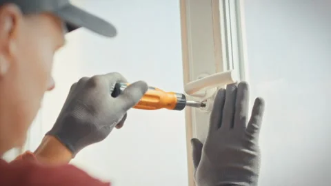 A technician in work uniform and gloves completes a plastic window repair ti Stock Footage 341489367