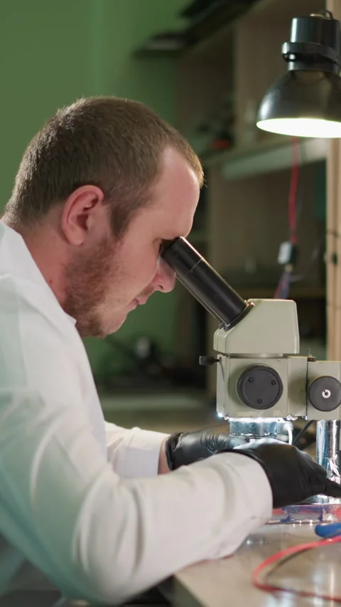 Technician Working on Electronic Component Under Microscope in Lab Stock Footage 310489323