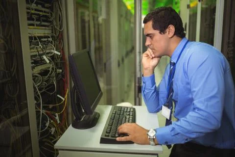 Technician working on personal computer while analyzing server Foto stock