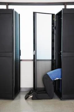 A technician working in the rack area of a computer server farm. Stock Photos