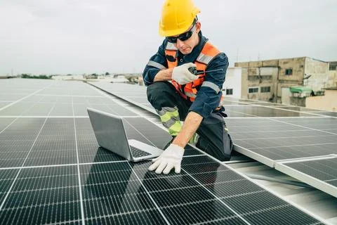 Technician working on solar panels on a rooftop in an urban setting during .. Stock Photos