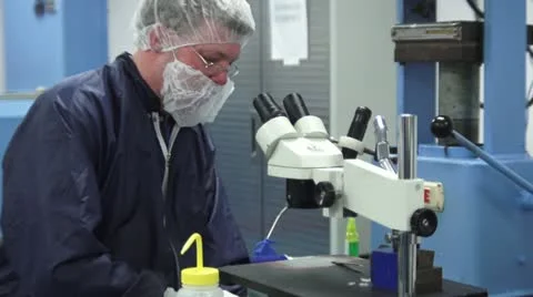Technician working at table in Cleanroom next to Microscope Stock Footage 10896132