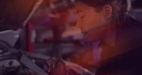 Technician working in workshop, tapping tablet and consulting repair guide with Stock Footage 311584915