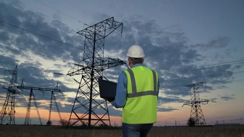 Technician works with network data on laptop walking to power transmission lines Stock Footage 268055599