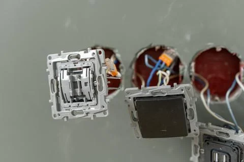 Technicians are seen installing electrical switch plates in wall openings Stock Photos