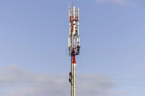 Technicians assembling antennas for 5G on a telecommunications tower. Stock Photos
