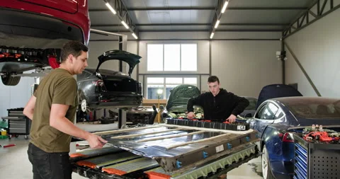 Technicians Assembling Electric Car Battery On Workshop Platform Stock Footage 277304333