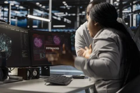 Technicians in data center viewing hacking security breach alert Stock Photos