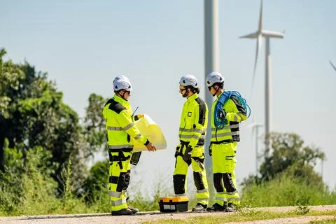Technicians discussing maintenance plan at wind farm on a clear day with tu.. Stock Photos