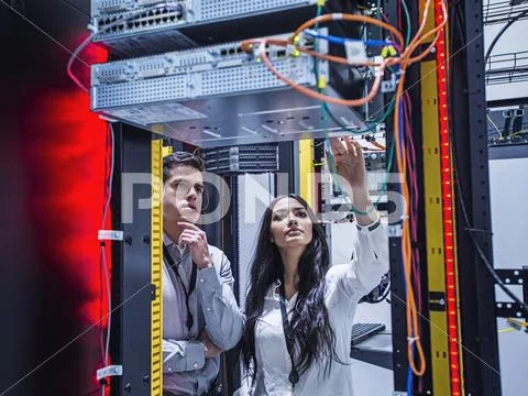 Technicians Examining Computer In Server Room