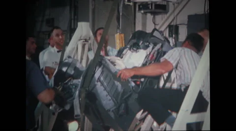 Technicians guiding to remove spacecraft couch off stand Stock Footage 37597008