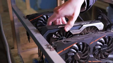 Technician's hand installing graphics card into custom-built mining rig for.. Stock Photos