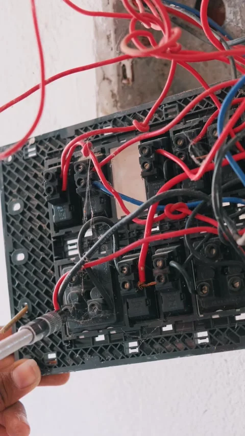 A technician's hand repairing complex internal wiring of a modular switchboard Vidéo 332998046