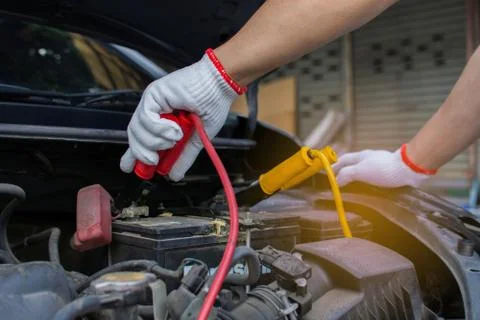 Technician's hand uses a charging cable for car batteries. Foto stock