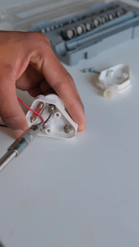 Technician's hand wiring a black electrical cable into an open three-pin plug 스톡 동영상 332998594