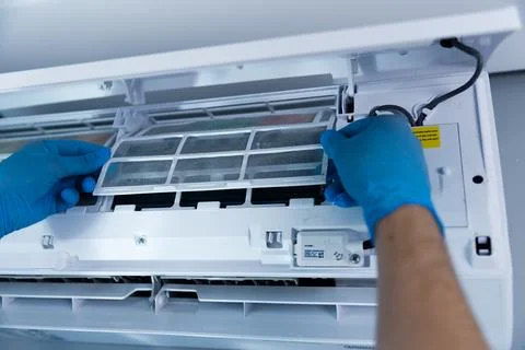 A technicians hands in blue gloves are removing an air conditioning filter from Stock-Fotos