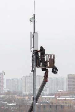 Technicians install mobile signal amplification devices on tower. It's nasty. Stock Photos