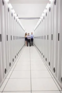 Technicians standing at end of server corridor Stock Photos