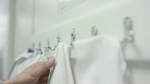 Technicians taking offir laboratory coat from hook in dressing room Stock Footage 107963219