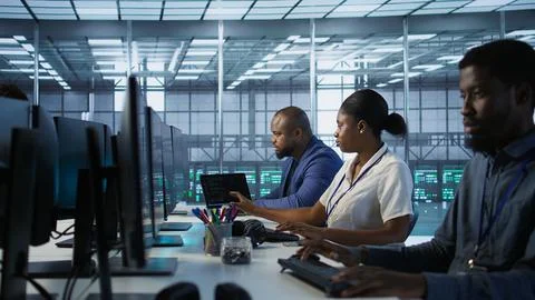 Technicians using computers and tablet in data center, implementing AI Stock Photos