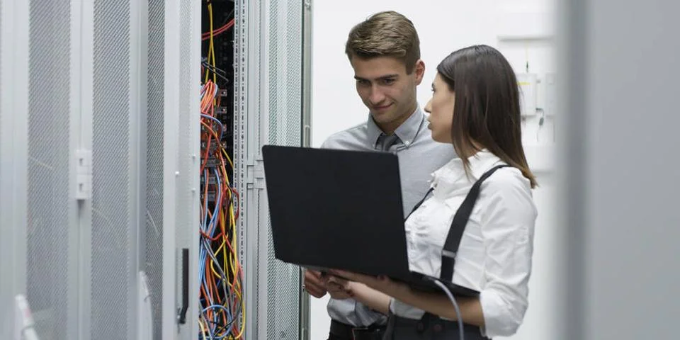 Technicians using laptop while analyzing server in server room Technicians... Stock-Fotos