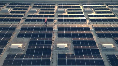 Technicians walking along solar panel array at sunset aerial tracking shot Stock Footage 278672992