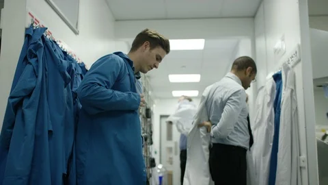 Technicians wearing laboratory coat in dressing room to visit production area Stock Footage 107963834
