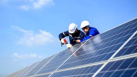 Technicians workers installing solar panels at solar cell farm Stock Photos