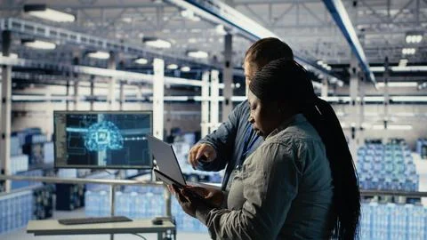 Technicians working together in server room, optimizing deep learning AI systems 写真素材