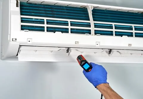Technitian checking temperature by infrared thermometer inside of Gree air co Stock Photos