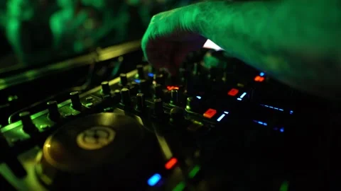 Techno DJ operating professional mixer equipment during a late party inside a Stock Footage 331566030